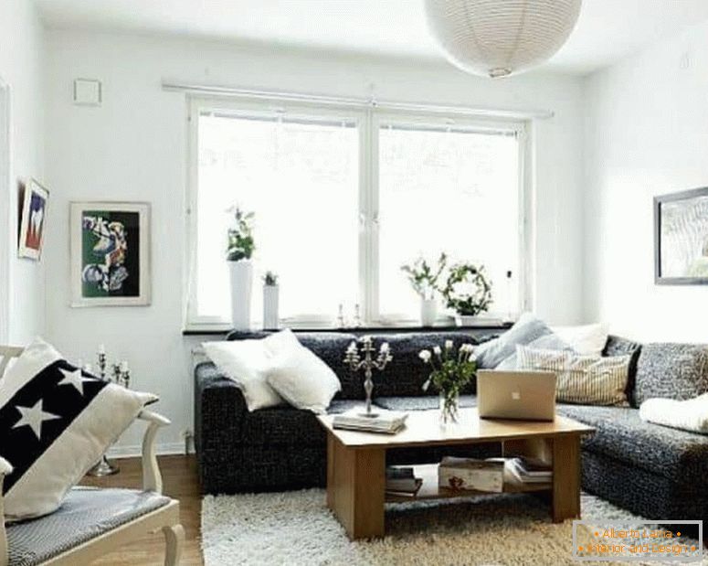 Malá obývacia izba v bielej farbe s tmavou rohovou pohovkou a oknom