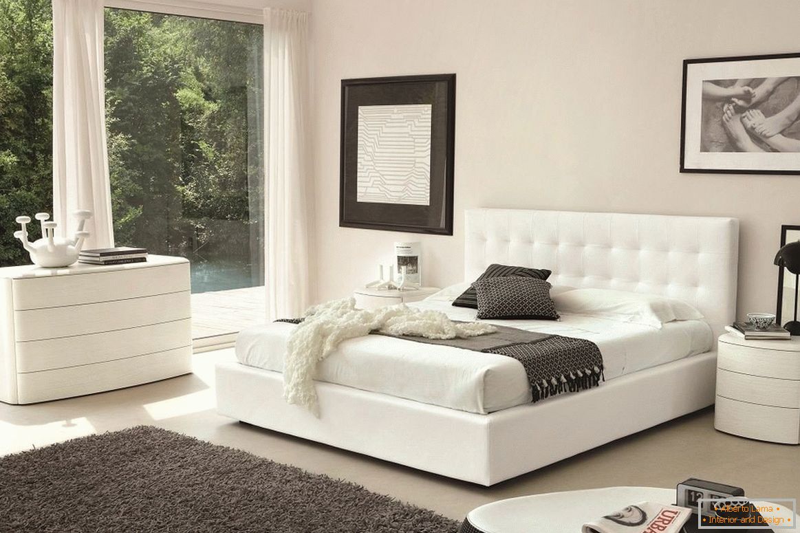 Biela posteľ, zásuvkové skrine a nočný stolík v spálni