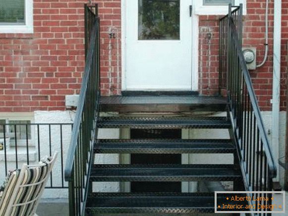 Malá kovová veranda so schodiskom do tehlového domu