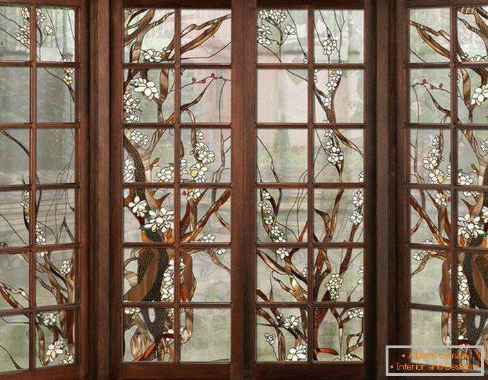 Okná v tmavom drevenom ráme sú zdobené farebným sklom. Nekomplikovaná postava vhodná pre dizajn interiéru v štýle krajiny alebo modernej.