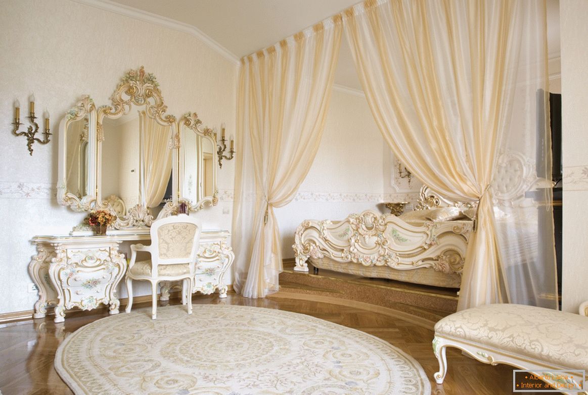 Rámovacie zrkadlá a dekoračné prvky nábytku sú vyrobené v jednom štýle s použitím zlata. Aby sa ušetrilo miesto, posteľ je skrytá v výklenku ohraničenom závesmi.