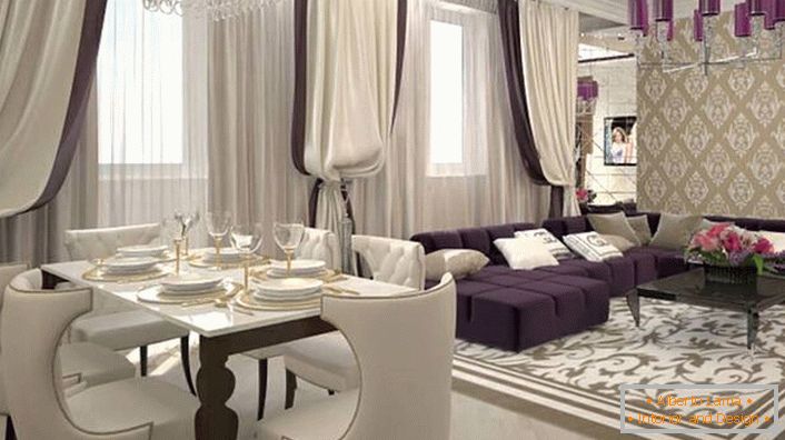 Ťažké závesy na oknách v kombinácii s mäkkým nábytkom bieleho lila sa spájajú, aby vytvorili interiér v štýle art deco. V súlade so štýlom je tiež vybrané osvetlenie. Stropný lustr je zdobený rovnakými lesklými odtieňmi tmavo fialovej farby.