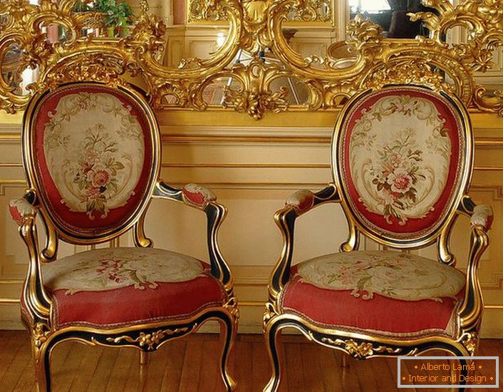 Otvorená štuková štuková farba na zrkadle a stoličky s červeným mäkkým čalúnením - jasnými predstaviteľmi barokového štýlu.