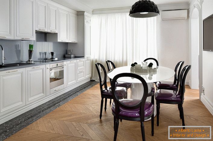 Biela interiérová kuchyňa s diakritikou tmavo šedej v eklektickom štýle. Zaujímavé stoličky s priehľadnými chrbtami a fialovým mäkkým čalúnením.