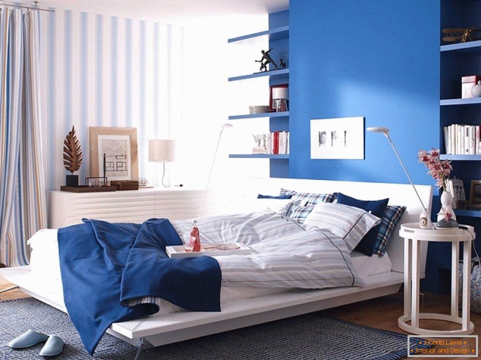 Modrá stena v spálni kombinovaná s pruhovanými tapetami
