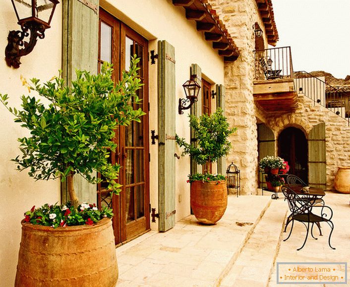 Terasa в средиземноморском стиле украшают горшки с живыми растениями. Привлекательный дизайн, мебель с витиеватыми спинками, керамические горшки создают уютную, расслабляющую атмосферу. 