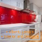 Biely nábytok a červená zástera v interiéri kuchyne