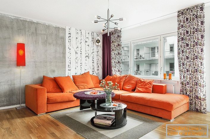 Škandinávsky štýl je vlastný používaniu teplých farieb v dizajne interiéru. Mäkká oranžová pohovka ekologicky vyzerá na pozadí stien mrazuvzdorného odtieňa.