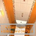 Kombinácia bielej a oranžovej dlažby v dizajne toalety