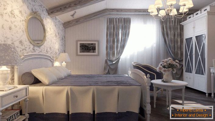 Spálňa v štýle krajiny je vyrobená v tlmených modrých tónoch. Stenu v hlave postele je pokrytá tapetou s kvetinovým vzorom.