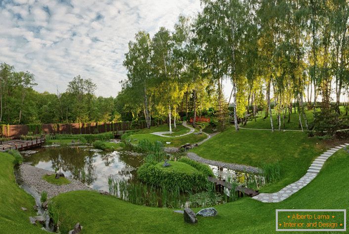 Umelý rybník za domom, ktorý je vyzdobený v štýle chaty. Neobvyklé, odvážne riešenie pre dizajn krajiny.