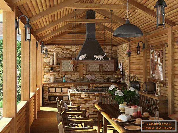 Malá kuchyňa s grilom na verande vidieckeho domu. Štátny štýl je dokázaný predovšetkým dekoráciou stien a stropu s dreveným rámom.
