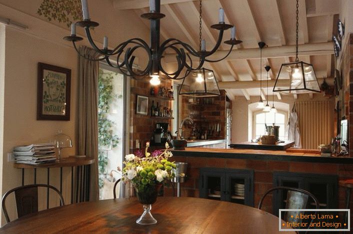 Jedáleň a kuchyňa sú vyzdobené v štýle krajiny. Čo je pozoruhodné, je lustr nad stolom, ktorý osvetľuje priestor pomocou bežných voskových sviečok. Tenký dizajn nápad, pretože v miestnosti je aj tradičné osvetlenie, ktoré pracuje z elektrickej siete.