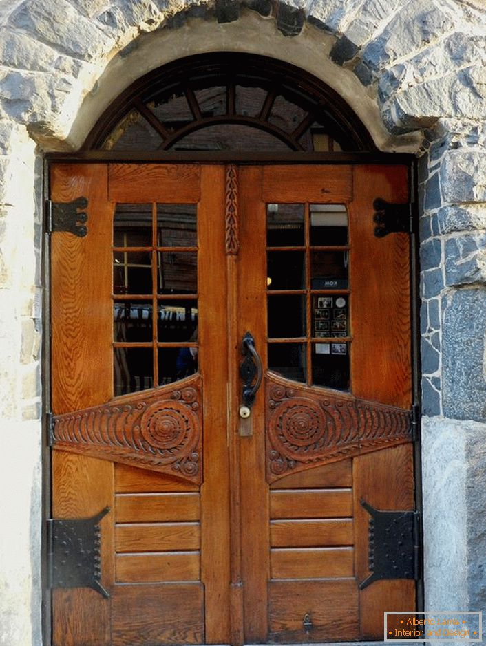 Dvere v secesnom štýle zdobia predné dvere vidieckej chatky s fasádou z prírodného kameňa. 