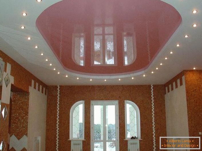 Ružový oválny strečový strop s LED osvetlením vo veľkej miestnosti v dedinskom dome.