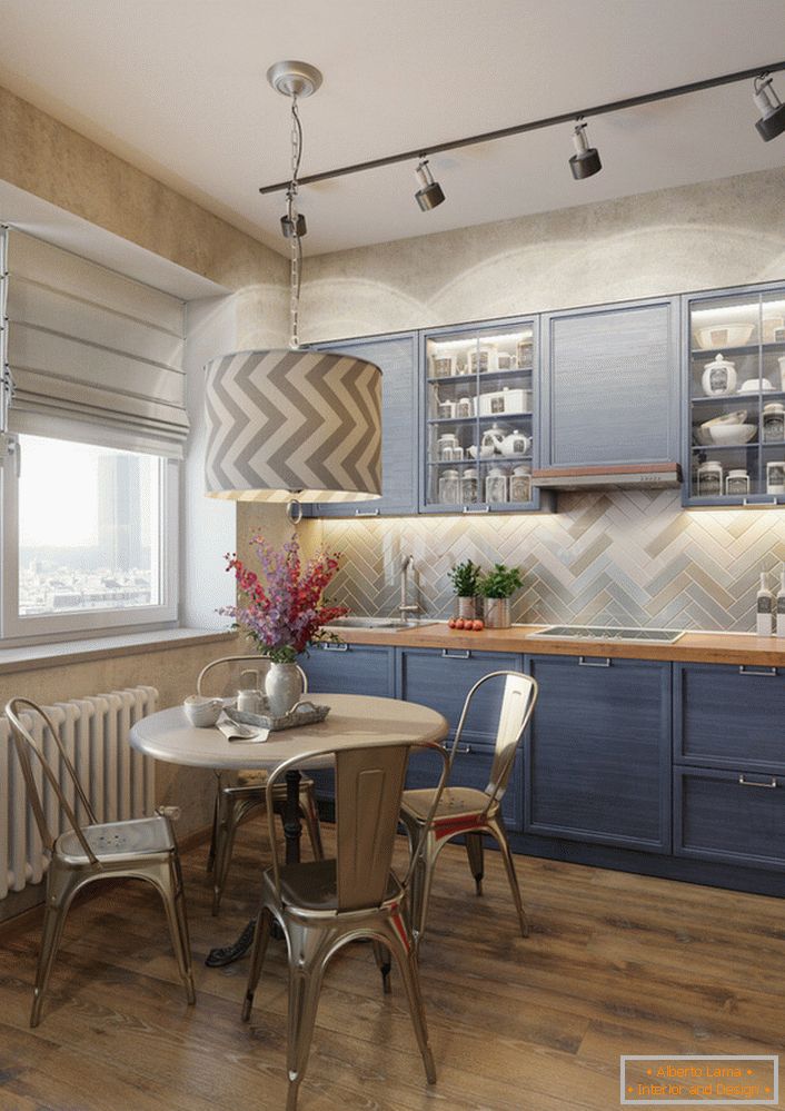 Svetlá modrá farba kuchynského setu je vynikajúcim riešením pre eklektickú kuchyňu. Príklad dokonale zvoleného osvetlenia, ktoré samostatne osvetľuje pracovnú plochu a jedálenský stôl.
